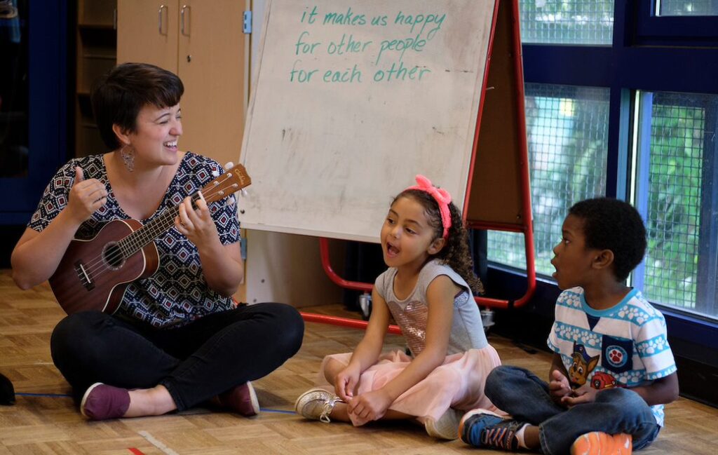 Woman playing ukelele with children singing