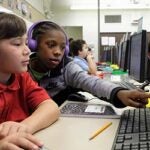 Two students work together at a computer in a classroom