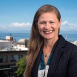 Chandra Hampson smiles for a photo with the city and sound behind her.