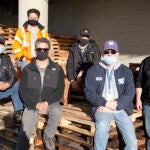 A group of six men pose for a photo outside the warehouse.