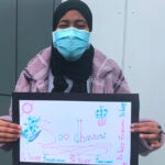 A student holds a sign that says welcome in Somali