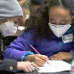 Two middle-school age students work together on a project in a classroom