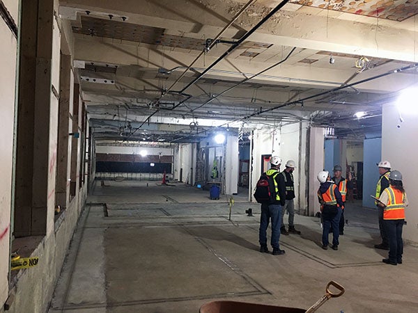 workers standing in a large open area in a building under construction