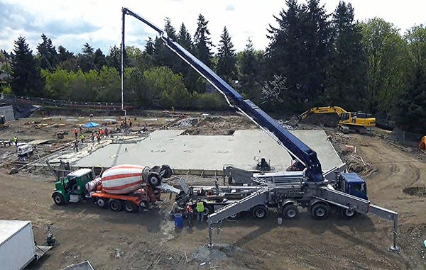 a concrete mixer sites in front of a concrete slab being poured