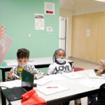 A City Year employee talks with a group of elementary students in a classroom