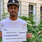 A student holds a large check that represents a scholarship.