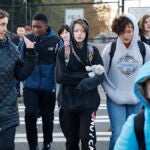 Students and adults walk together across a crosswalk