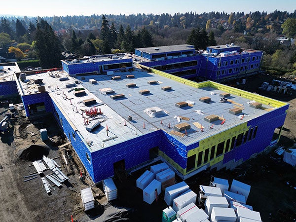 aerial view of a part of a large building with blue walls and construction equipment