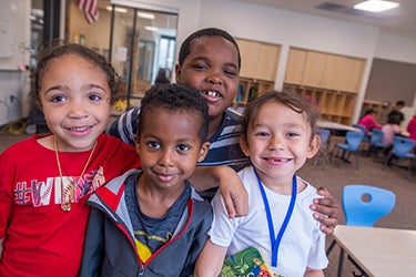 Four students pose for a photo in a classroom