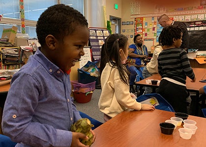 A young student tries new food in a South Shore classroom