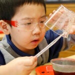 A young student in safety glasses works on a project