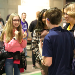 Three students stand together at an event signing