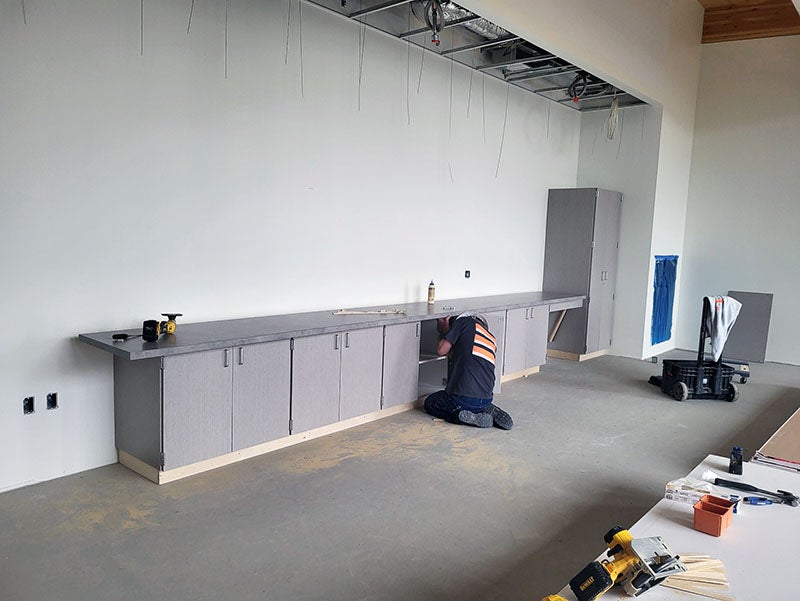 cabinet and counter top being installed by a worker in a large room