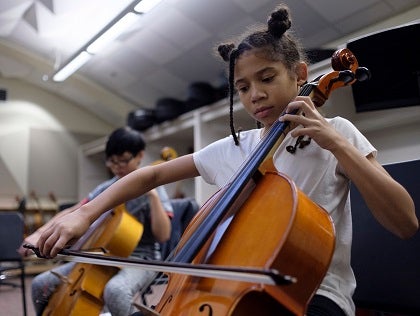 Two students play cellos in a music classroom.