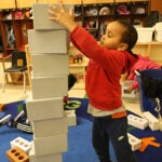A young student stacks blocks in a classroom