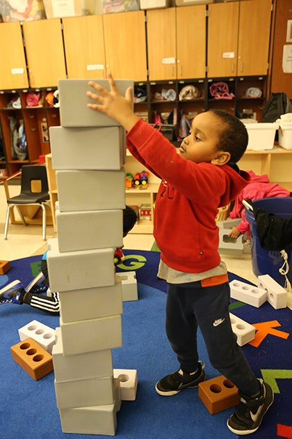 A young student stacks blocks in a classroom