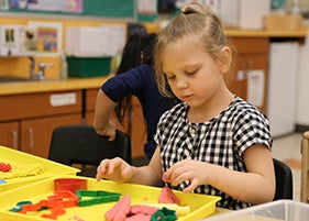 A young student plays with preschool toys in a classroom