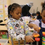 Two students in a classroom build blocks together