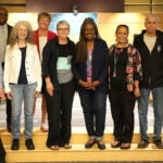 A group of staff stand together in the JSC auditorium