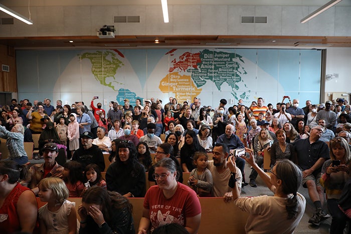 a large group of people in front of a wall with a map
