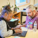 Family Resource Center staff types into computer while talking with a family member.