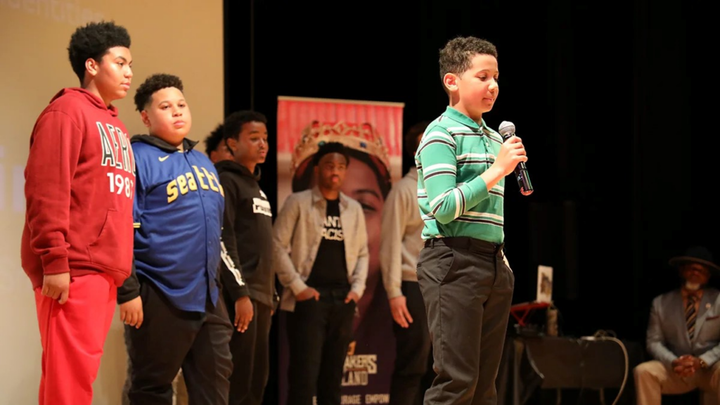 Kingmakers student with microphone preparing to speak to the audience