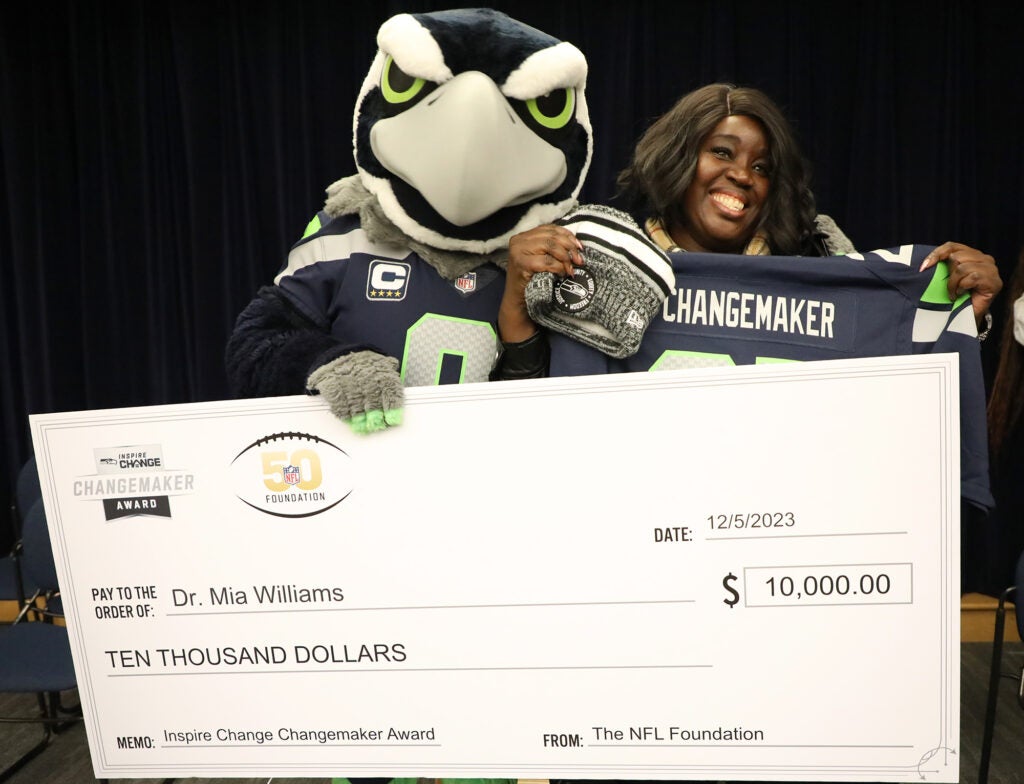Dr. Mia Williams and Seahawks mascot hold a giant $10,000 check awarded by NFL Changemaker.