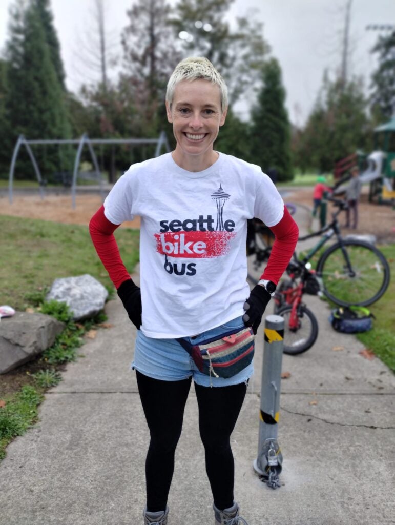 volunteer standing at park wearing "Seattle Bike Bus" t-shirt