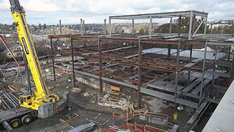a steel framework for a 3 story building with a crane partially showing in the foreground