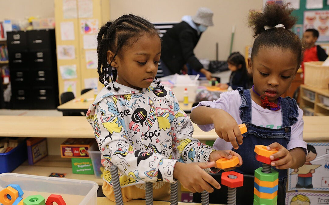 Two students in a classroom build blocks together