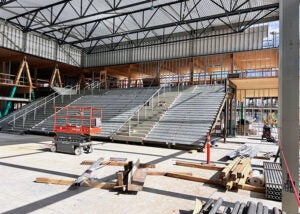 large interior room under construction with framing on one side for stairs. there is materials and equipment in the space.