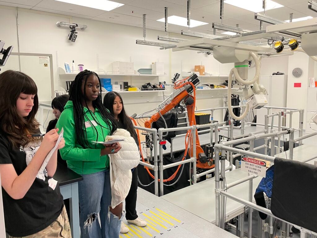 Students look at machine designed to simulate limb movement