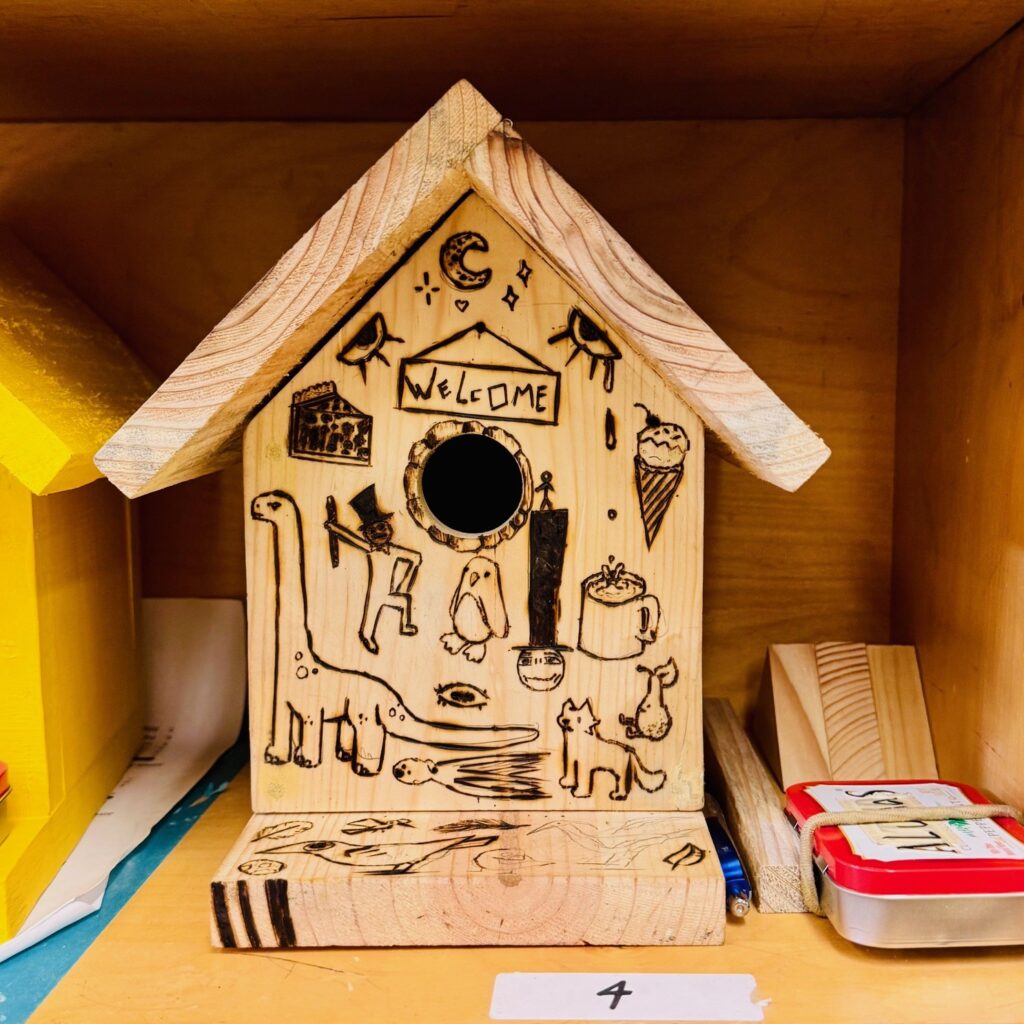 Bird house with various animals etched into it with "welcome" written above the entry hole