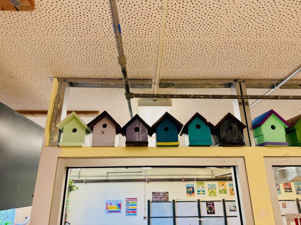 Bird houses of green and grey stacked above a doorway