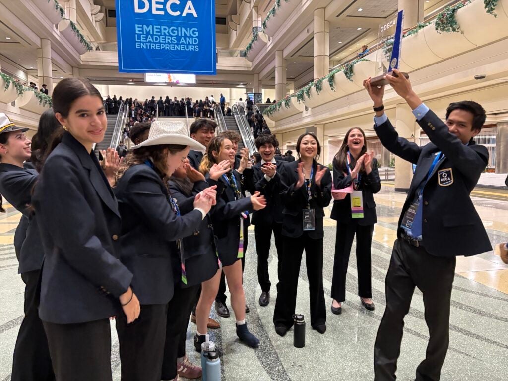 SPS students laughing in hallway with student holding prize in front of group