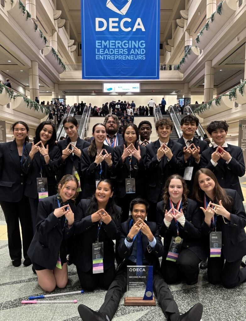 Students pose under DECA sign