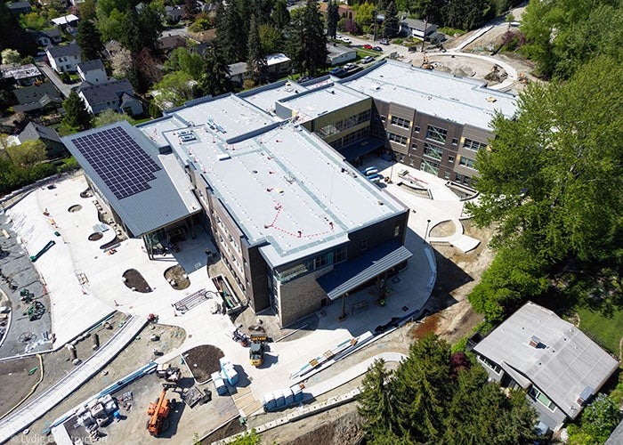 Overhead view of the building layout with flat roofs, solar panels, and ongoing landscaping around the perimeter.