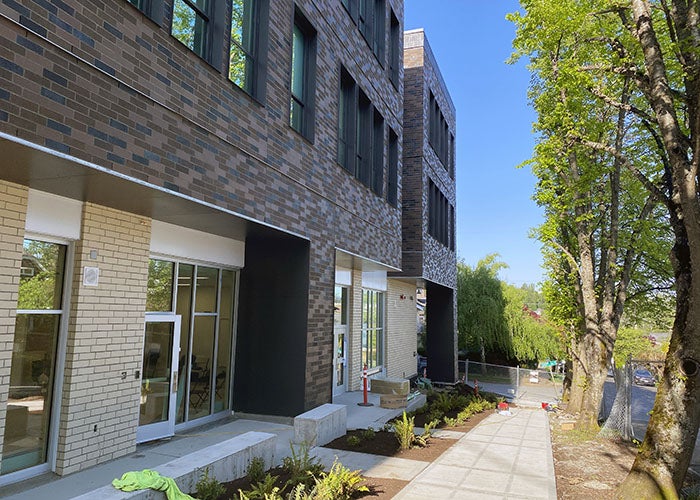 Close-up of the sidewalk running alongside the new school wing, showing its textured brick exterior and fresh planting beds.