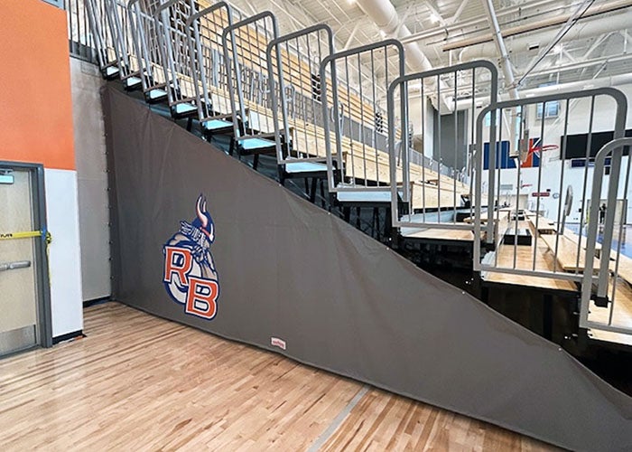 Close-up of the gym bleachers with “RB” Viking mascot branding on protective padding below the stands.