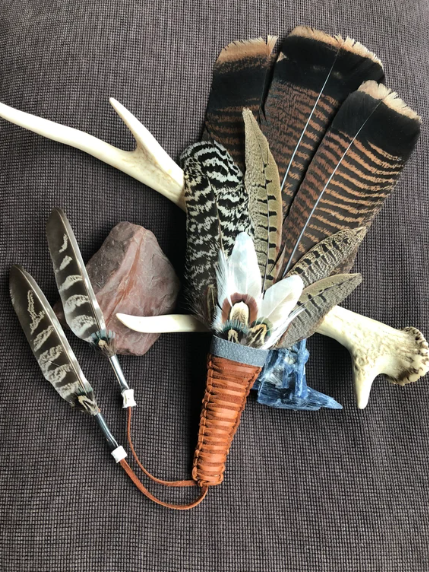Image of a fan made our of feathers with a leather wrapped handle