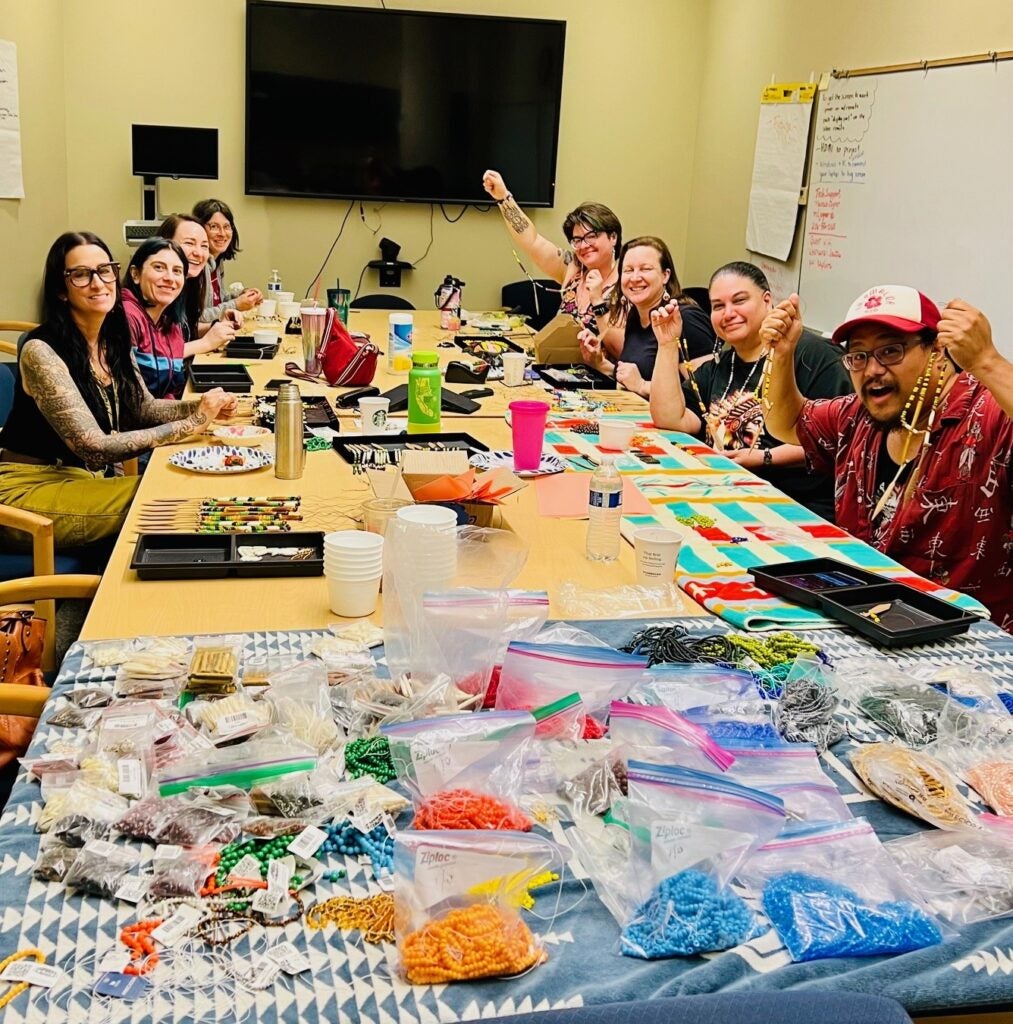 Group of people making beaded necklaces