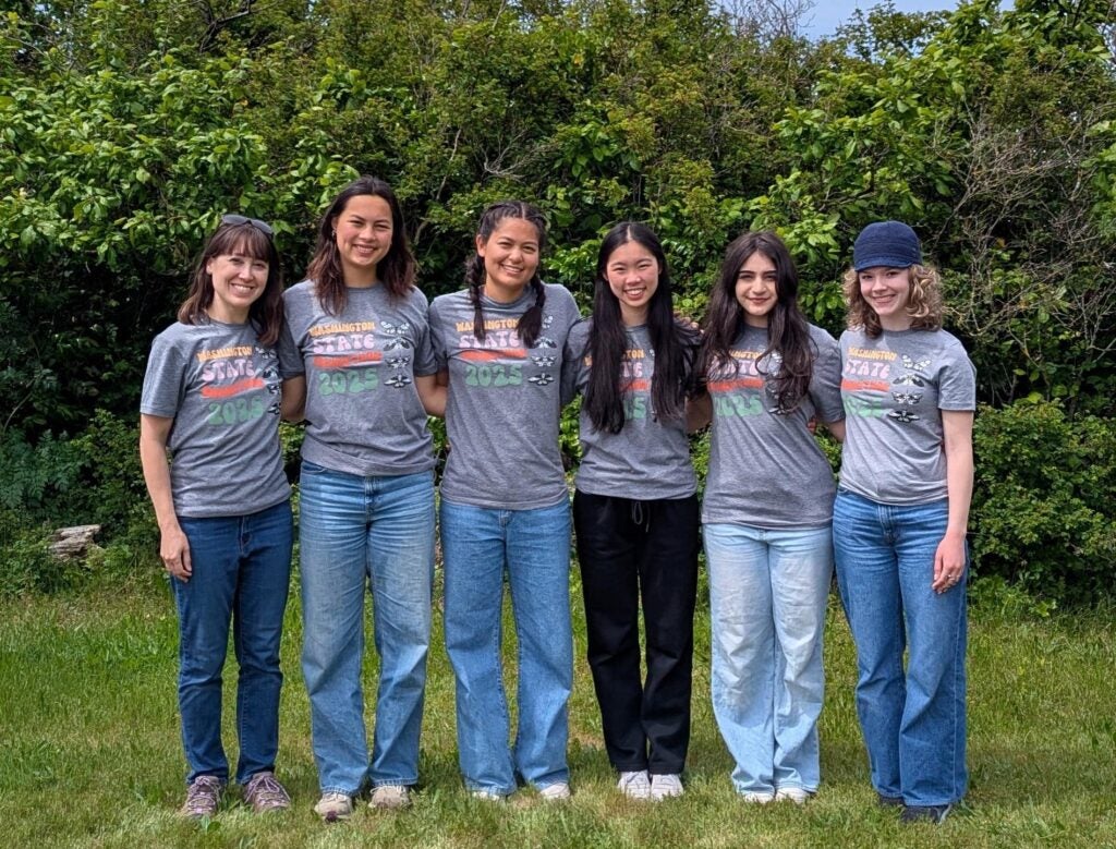 Group of students in matching t-shirts standing in front of trees