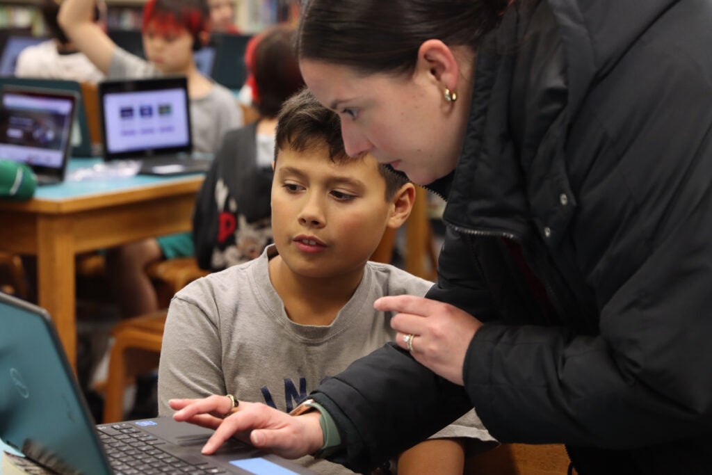 Student and staff person working on a laptop