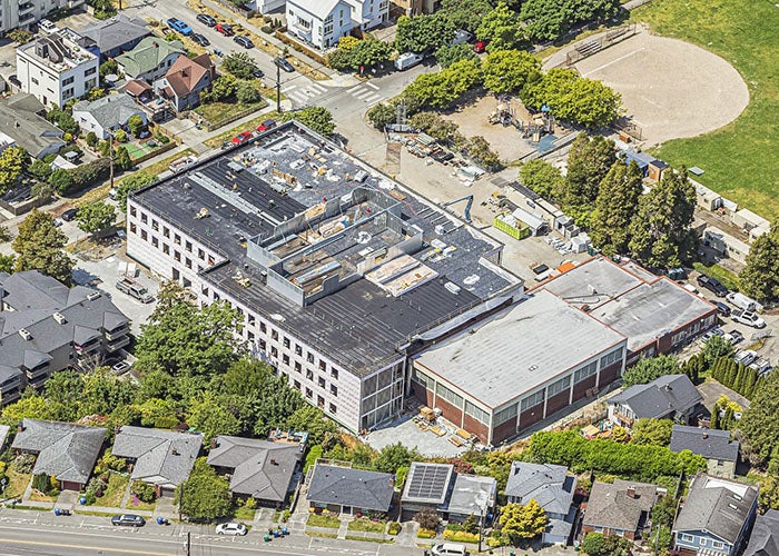 aerial of school with construction equipment on roof and in grounds