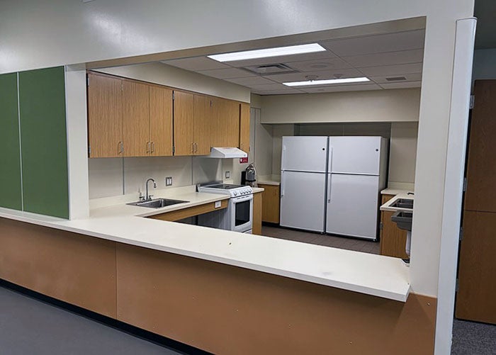 a view through an interior opening of a kitchen space with stove, sink, and two refrigerators
