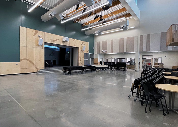 a large space with a stage and tables/chairs to one side