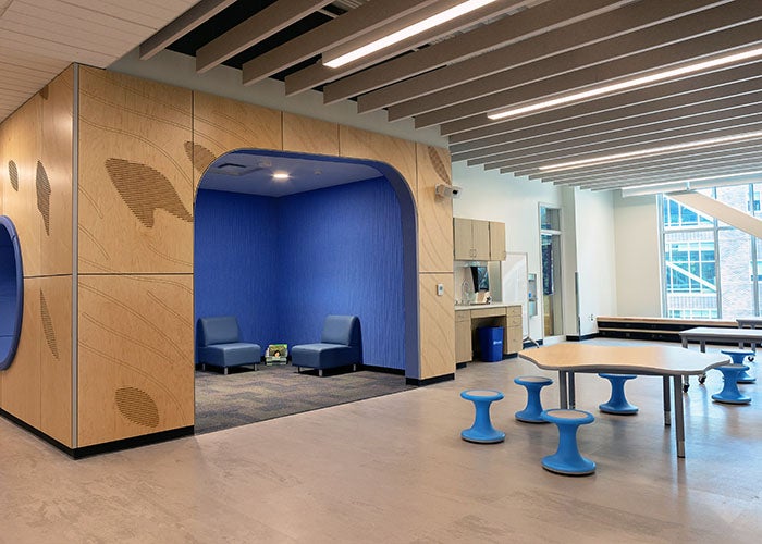 an open space with tables and an enclosed area with blue walls and seating