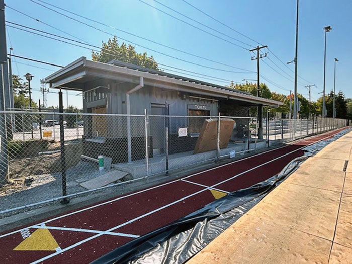 a small building behind a chain link fence with a track inside the fence