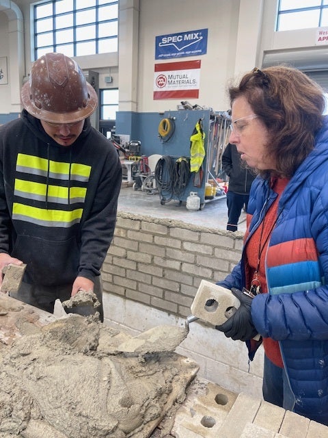 teacher and apprentice viewing cement in large warehouse