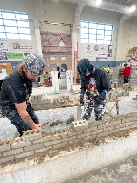 student practicing bricklaying in warehouse